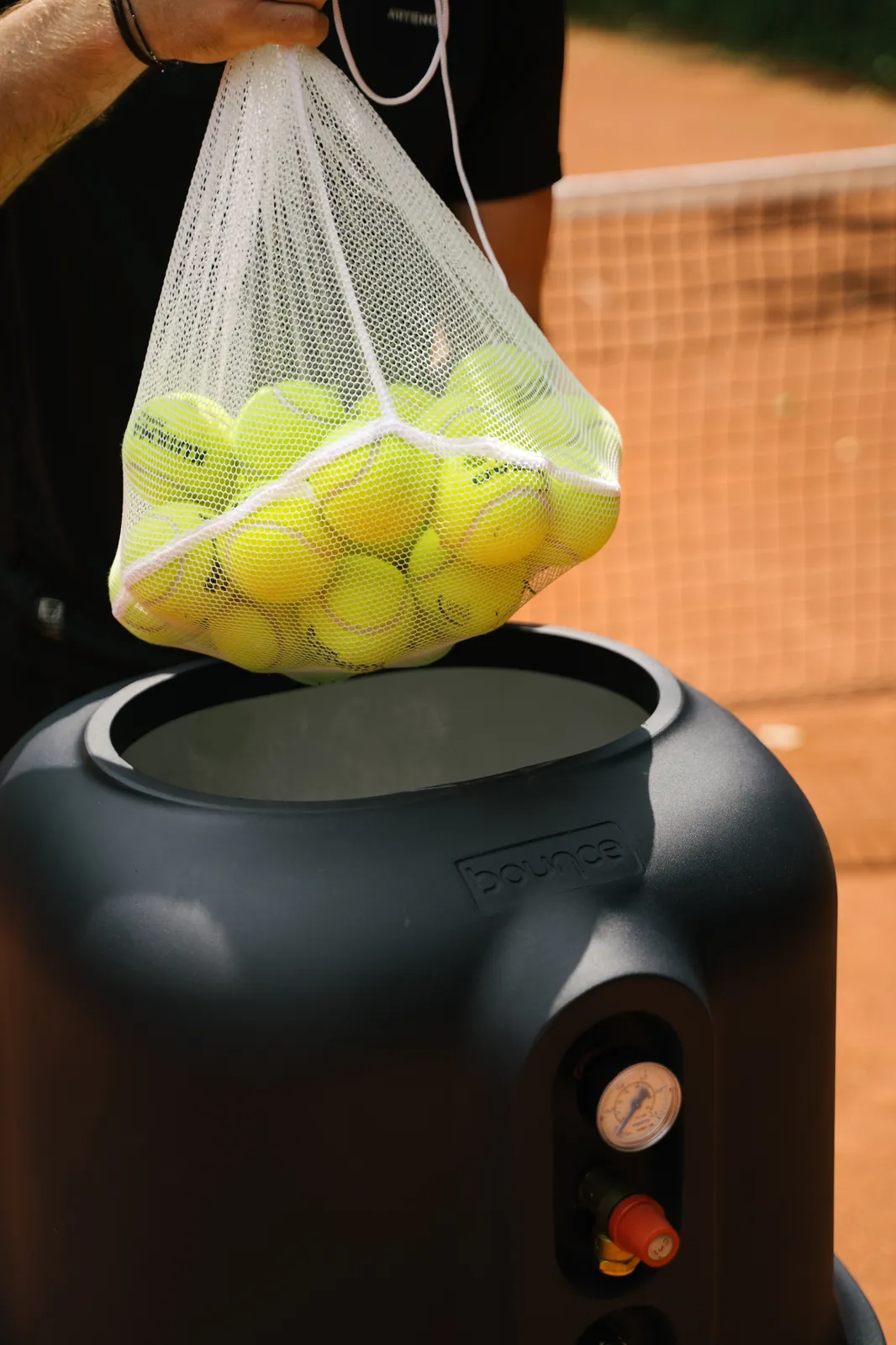 Jugador vaciando una bolsa de pelotas de tenis dentro del Bounce Pro abierto